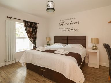 A bedroom with a double bed, bedside tables with lamps, a window with curtains, and a wall decal at The Five Bells Inn in Upwell