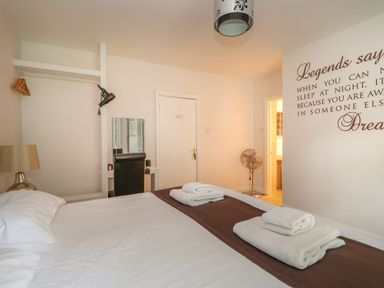 A bedroom with a bed with white sheets and towels a lamp a fan a desk with a chair and a wall decal at The Five Bells Inn in Upwell