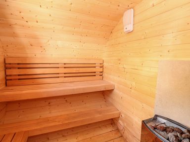 An interior view of a wooden sauna with benches and a heater with stones at The Five Bells Inn in Upwell