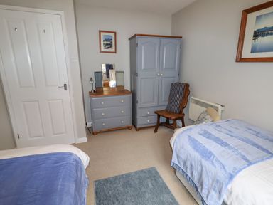 A bedroom with two single beds blue blankets and wooden furniture at 9 Oakley Wharf in Porthmadog