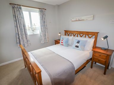 A bedroom with a wooden bed and two nightstands with lamps at 9 Oakley Wharf in Porthmadog