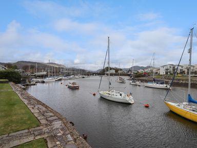 A marina with sailboats and houses along the shoreline at 9 Oakley Wharf in Porthmadog