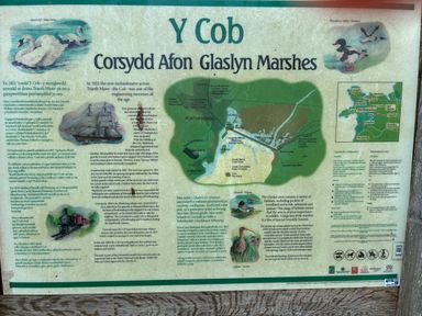 An informational board about Y Cob Corsydd Afon Glaslyn Marshes with historical text a map and bird illustrations at 9 Oakley Wharf in Porthmadog