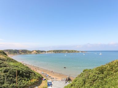 A coastal bay with a sandy beach boats in the water and green hills surrounding at Sea Cliff in Morfa Nefyn