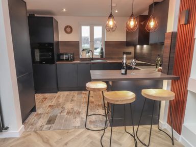 A kitchen with a breakfast bar and three stools at Sea Cliff in Morfa Nefyn