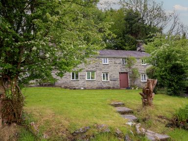 A house with a pathway and trees at The Long House in Penmachno