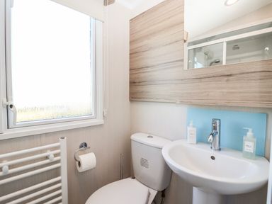 A bathroom with a toilet sink mirror and window at Lazy Dayz Lodge in East Heslerton near Malton