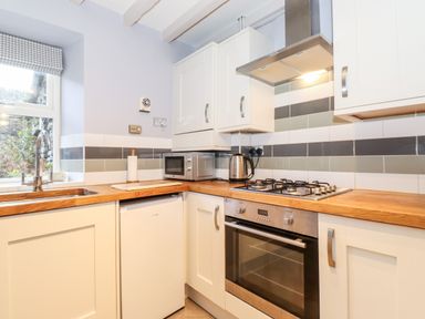 A kitchen with a wooden countertop a sink a microwave kettle gas stove and oven at Fell View in Ambleside