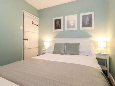 A bedroom with a double bed two bedside tables with lamps and three leaf pictures on the wall at Fell View in Ambleside