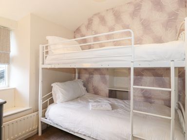 A bedroom with a white metal bunk bed and a window with a checked blind at Fell View in Ambleside