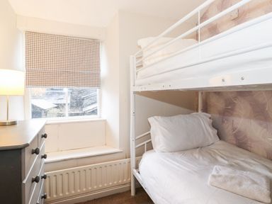 A small bedroom with a bunk bed a chest of drawers and a window with a checkered blind at Fell View in Ambleside