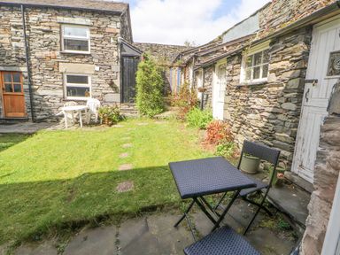 A stone courtyard with two patio tables and chairs and plants at Fell View in Ambleside