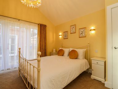 A bedroom with a metal bed frame white bedding round pillows and bedside tables at Summerseats Cottage in Alnwick