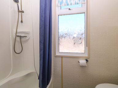A shower with a curtain and a toilet at 25 Foxburrow Hang in Fritton near Belton