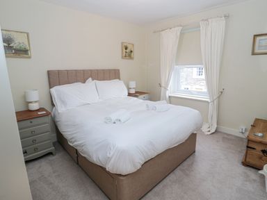 A bedroom with a bed and white linens beside two nightstands with lamps at The Haven in North Sunderland near Seahouses