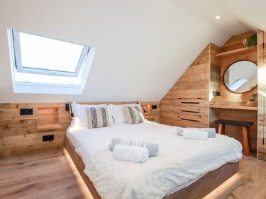 A bedroom with a bed and rolled towels near a skylight window at Little Beach Cabin in Crantock