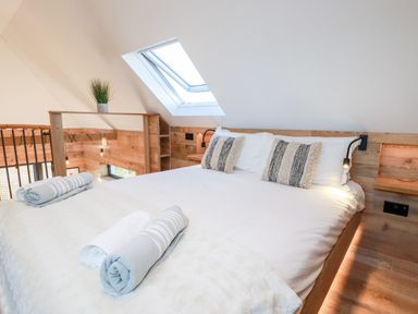 A bedroom with a white bed and striped pillows under a skylight window at Little Beach Cabin in Crantock