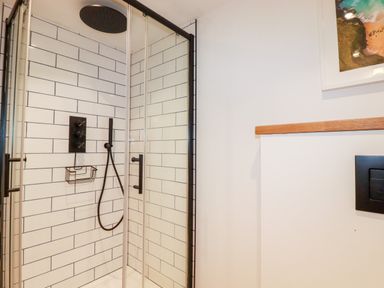 A tiled shower enclosure with black fixtures and glass doors in a bathroom at Little Beach Cabin in Crantock