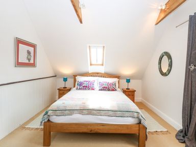 A bedroom with a wooden bed and two bedside tables with lamps at The Hayloft in Haddiscoe
