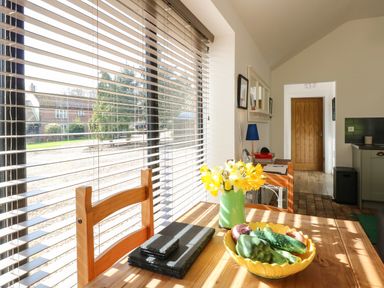 A kitchen table with vegetables and flowers near a window with blinds at The Grain Store in Haddiscoe