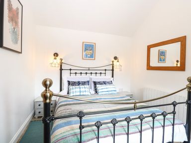 A bedroom with a metal bed frame bedside tables wall lamps and a mirror at The Grain Store in Haddiscoe