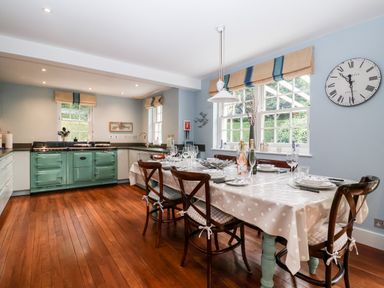 A kitchen with a dining table set for a meal and a green stove at Lampland House in Walberswick