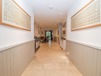 A hallway with tiled floor paintings on walls and furniture at Lampland House in Walberswick