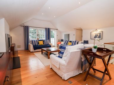 A living room with two sofas a coffee table a TV stand wooden floors and a tray table at Lampland House in Walberswick