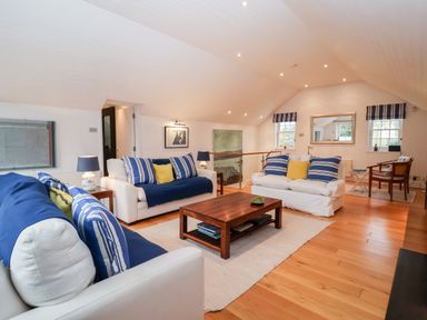A living room with white sofas and blue cushions a wooden coffee table and wooden flooring at Lampland House in Walberswick