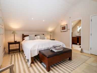 A bedroom with a bed side tables lamps rug and door leading to a bathroom at Lampland House in Walberswick