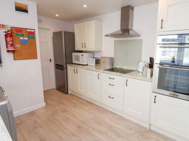 A kitchen with white cabinets a stainless steel fridge microwave toaster and double oven at Seascape Cottage in Seahouses