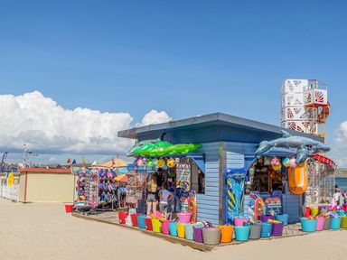 A beachside kiosk with inflatable toys and buckets on the sand at Brewers Quay Harbour