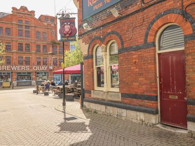 A street scene with a pub sign reading The Red Lion and outdoor seating near a large brick building with Brewers Quay signage at Brewers Quay Harbour