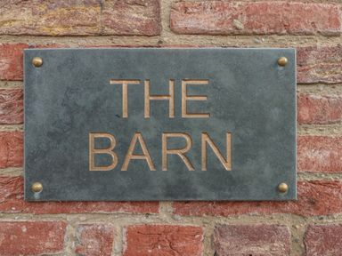A metal sign with the words THE BARN mounted on a brick wall at The Barn Helperby near Boroughbridge