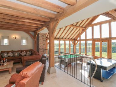 A living room with leather chairs and a sofa next to a games area with a pool table and air hockey table at The Barn Helperby near Boroughbridge