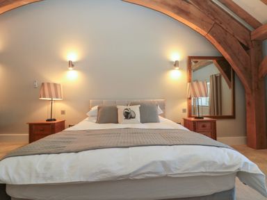 A bedroom with a bed bedside tables lamps and a large mirror at The Barn Helperby near Boroughbridge