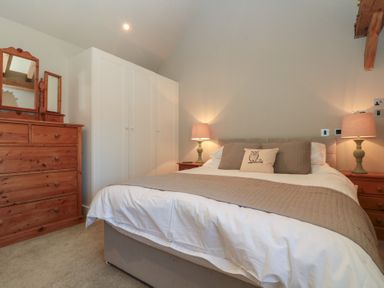 A bedroom with a double bed lamps on bedside tables a wooden dresser and white wardrobes at The Barn Helperby near Boroughbridge