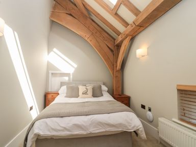 A bedroom with a double bed wooden beams on the ceiling and two bedside tables at The Barn in Helperby near Boroughbridge