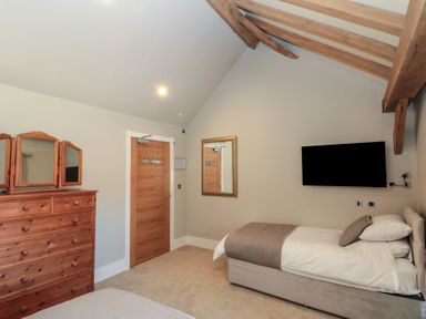 A bedroom with a single bed a wooden dresser a wall-mounted television and a mirror at The Barn Helperby near Boroughbridge