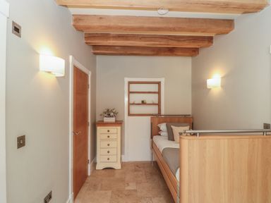 A small bedroom with a single bed wooden beams on ceiling a chest of drawers and a closed wooden door at The Barn Helperby near Boroughbridge