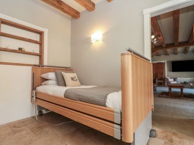 A bedroom with a single wooden bed and pillows next to a living room with a coffee table and sofa at The Barn Helperby near Boroughbridge