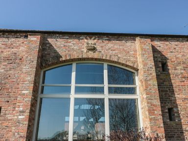 A large arched window on a brick wall with a blue sky at The Barn in Helperby near Boroughbridge
