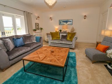 A living room with two sofas a patterned armchair a wooden coffee table and a teal rug at Hindon Hall in Lelant near Carbis Bay