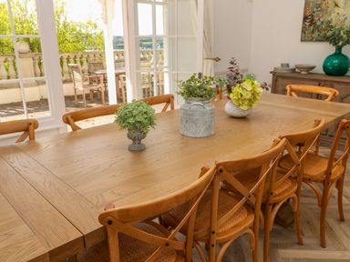 A dining room with a wooden table and chairs and three plant pots on the table at Hindon Hall in Lelant near Carbis Bay