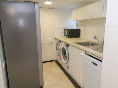 A laundry room with a refrigerator washing machine dryer microwave sink and dishwasher at Hindon Hall in Lelant near Carbis Bay