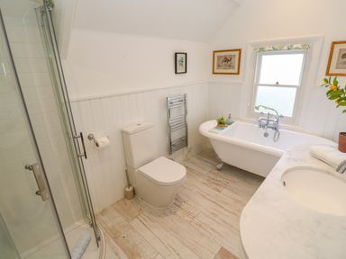 A bathroom with a shower enclosure toilet bathtub sink and framed pictures at Hindon Hall in Lelant near Carbis Bay