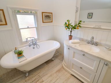 A bathroom with a clawfoot bathtub and a sink with a marble countertop at Hindon Hall in Lelant near Carbis Bay