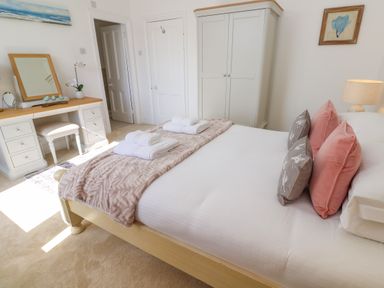 A bedroom with a bed with folded towels a vanity table with a mirror a wardrobe and a lamp at Hindon Hall in Lelant near Carbis Bay