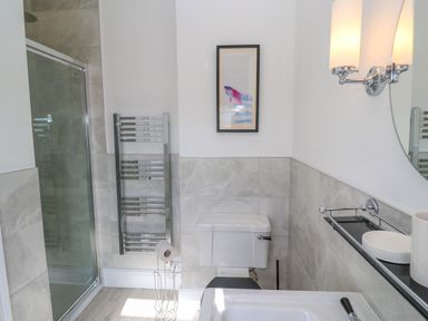 A bathroom with a shower enclosure a toilet a towel rack a framed picture and a wall light at Hindon Hall in Lelant near Carbis Bay