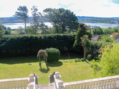 A garden with trimmed hedges trees and a lawn overlooking a river and hills at Hindon Hall in Lelant near Carbis Bay